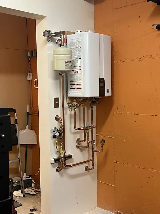 Plumbing technician inspecting water heater connections in Okmulgee